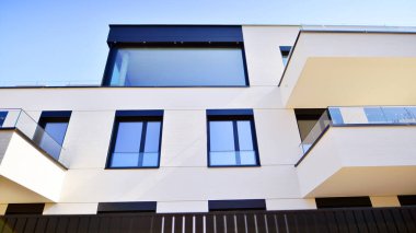Güneşli bir günde kentsel konut binalarının modern mimarisi. Büyük pencereleri ve geniş terasları olan düşük katlı apartmanlar. Modern bir apartmanın beyaz cephesi.