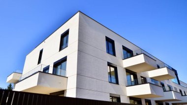 Güneşli bir günde kentsel konut binalarının modern mimarisi. Büyük pencereleri ve geniş terasları olan düşük katlı apartmanlar. Modern bir apartmanın beyaz cephesi.