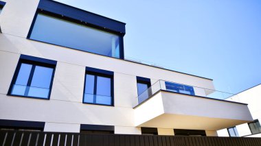 Güneşli bir günde kentsel konut binalarının modern mimarisi. Büyük pencereleri ve geniş terasları olan düşük katlı apartmanlar. Modern bir apartmanın beyaz cephesi.