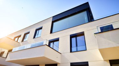 Güneşli bir günde kentsel konut binalarının modern mimarisi. Büyük pencereleri ve geniş terasları olan düşük katlı apartmanlar. Modern bir apartmanın beyaz cephesi.