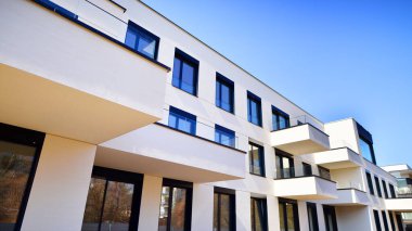 Güneşli bir günde kentsel konut binalarının modern mimarisi. Büyük pencereleri ve geniş terasları olan düşük katlı apartmanlar. Modern bir apartmanın beyaz cephesi.