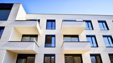 Güneşli bir günde kentsel konut binalarının modern mimarisi. Büyük pencereleri ve geniş terasları olan düşük katlı apartmanlar. Modern bir apartmanın beyaz cephesi.