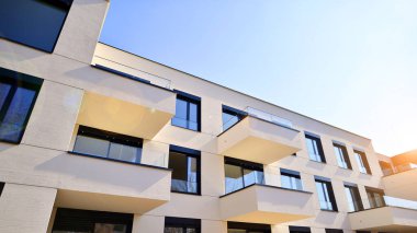 Güneşli bir günde kentsel konut binalarının modern mimarisi. Büyük pencereleri ve geniş terasları olan düşük katlı apartmanlar. Modern bir apartmanın beyaz cephesi.