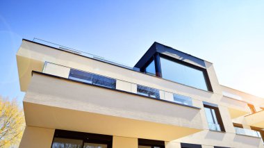 Güneşli bir günde kentsel konut binalarının modern mimarisi. Büyük pencereleri ve geniş terasları olan düşük katlı apartmanlar. Modern bir apartmanın beyaz cephesi.
