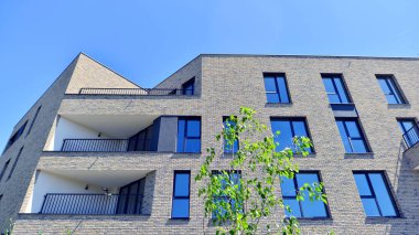 Çevre mimarisi. Yeşil ağaç ve yeni konut binası. Doğanın ve modernliğin ahengi. Yeşil yerleşim bölgesinde yeni daireleri olan modern bir apartman..