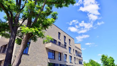 Çevre mimarisi. Yeşil ağaç ve yeni konut binası. Doğanın ve modernliğin ahengi. Yeşil yerleşim bölgesinde yeni daireleri olan modern bir apartman..