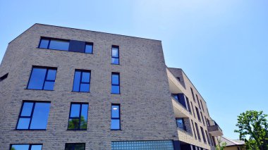 Çevre mimarisi. Yeşil ağaç ve yeni konut binası. Doğanın ve modernliğin ahengi. Yeşil yerleşim bölgesinde yeni daireleri olan modern bir apartman..