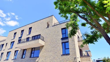 Çevre mimarisi. Yeşil ağaç ve yeni konut binası. Doğanın ve modernliğin ahengi. Yeşil yerleşim bölgesinde yeni daireleri olan modern bir apartman..