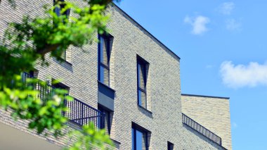 Çevre mimarisi. Yeşil ağaç ve yeni konut binası. Doğanın ve modernliğin ahengi. Yeşil yerleşim bölgesinde yeni daireleri olan modern bir apartman..