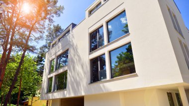 Çevre mimarisi. Yeşil ağaç ve yeni konut binası. Doğanın ve modernliğin ahengi. Yeşil yerleşim bölgesinde yeni daireleri olan modern bir apartman..