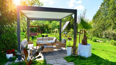 Güzel bahçesinde şık bahçe mobilyaları olan modern alüminyum pergola..