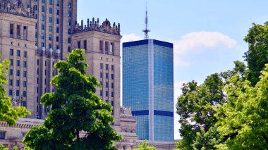 Modern şehir için ilham verici bir manzara. Cam ve metalden yapılmış binanın duvarı ağaçlara karşı. Kurumsal yapı ve ekoloji, mavi gökyüzü ve yeşil ağaçlı modern bina manzarası. 