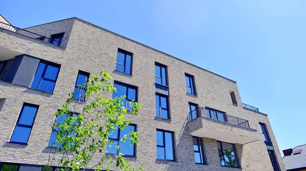 Çevre mimarisi. Yeşil ağaç ve yeni konut binası. Doğanın ve modernliğin ahengi. Yeşil yerleşim bölgesinde yeni daireleri olan modern bir apartman..