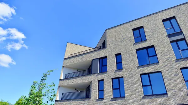 Çevre mimarisi. Yeşil ağaç ve yeni konut binası. Doğanın ve modernliğin ahengi. Yeşil yerleşim bölgesinde yeni daireleri olan modern bir apartman..