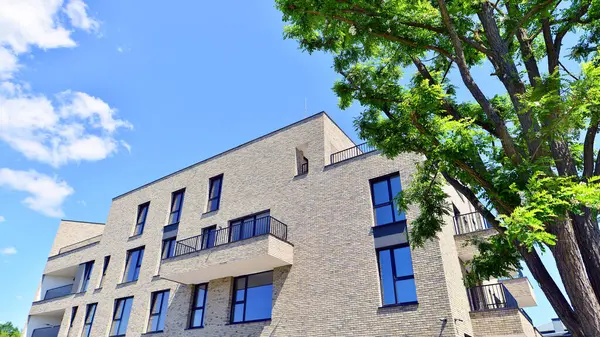 Çevre mimarisi. Yeşil ağaç ve yeni konut binası. Doğanın ve modernliğin ahengi. Yeşil yerleşim bölgesinde yeni daireleri olan modern bir apartman..