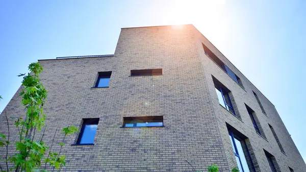 Çevre mimarisi. Yeşil ağaç ve yeni konut binası. Doğanın ve modernliğin ahengi. Yeşil yerleşim bölgesinde yeni daireleri olan modern bir apartman..