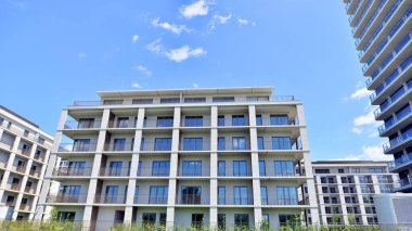 Mavi gökyüzü olan güneşli bir günde modern apartman binaları. Modern bir apartmanın ön cephesi. Modern konut binası kompleksi.
