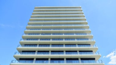 Çok katlı, modern bir apartmanın dış cephesi, pencereleri ve balkonları..