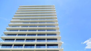 Çok katlı, modern bir apartmanın dış cephesi, pencereleri ve balkonları..