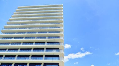 Çok katlı, modern bir apartmanın dış cephesi, pencereleri ve balkonları..