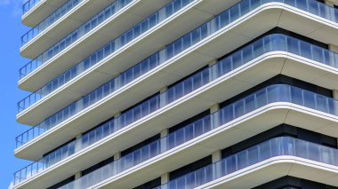 Çok katlı, modern bir apartmanın dış cephesi, pencereleri ve balkonları. Modern cam balkon parmaklıkları.