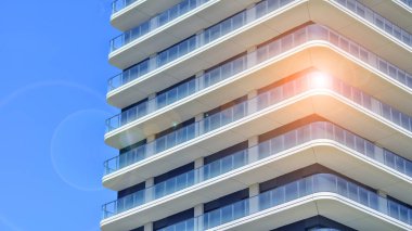 Çok katlı, modern bir apartmanın dış cephesi, pencereleri ve balkonları. Modern cam balkon parmaklıkları.