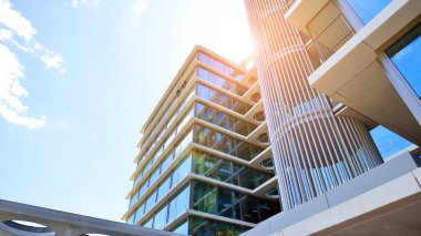 Cam cepheli modern ofis binası. Ofis binasının şeffaf cam duvarı. Binanın ön cephesinde mavi gökyüzünün yansıması.