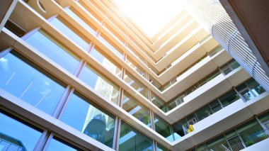 Cam cepheli modern ofis binası. Ofis binasının şeffaf cam duvarı. Binanın ön cephesinde mavi gökyüzünün yansıması.