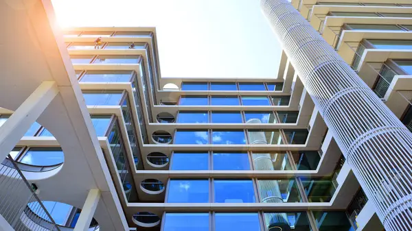 Cam cepheli modern ofis binası. Ofis binasının şeffaf cam duvarı. Binanın ön cephesinde mavi gökyüzünün yansıması.