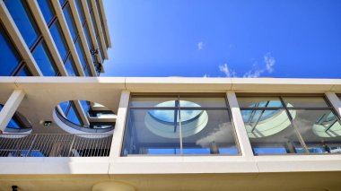 Cam cepheli modern ofis binası. Ofis binasının şeffaf cam duvarı. Binanın ön cephesinde mavi gökyüzünün yansıması.