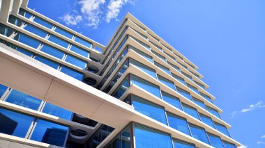 Şehir merkezindeki işletme bölgesi mimarisi. Mavi gökyüzüne ve güneş ışığına karşı cam yansıtıcı ofis binaları. Ekonomi, finans, iş faaliyeti konsepti. Soyut modern mimari parçası