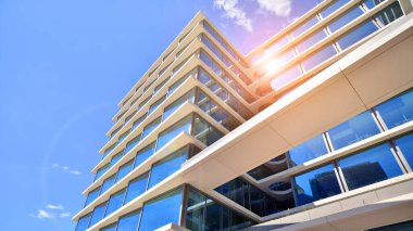 Şehir merkezindeki işletme bölgesi mimarisi. Mavi gökyüzüne ve güneş ışığına karşı cam yansıtıcı ofis binaları. Ekonomi, finans, iş faaliyeti konsepti. Soyut modern mimari parçası