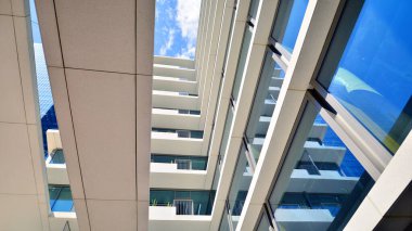 Şehir merkezindeki işletme bölgesi mimarisi. Mavi gökyüzüne ve güneş ışığına karşı cam yansıtıcı ofis binaları. Ekonomi, finans, iş faaliyeti konsepti. Soyut modern mimari parçası