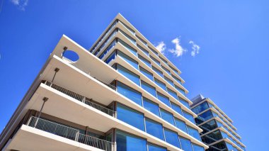 Şehir merkezindeki işletme bölgesi mimarisi. Mavi gökyüzüne ve güneş ışığına karşı cam yansıtıcı ofis binaları. Ekonomi, finans, iş faaliyeti konsepti. Soyut modern mimari parçası