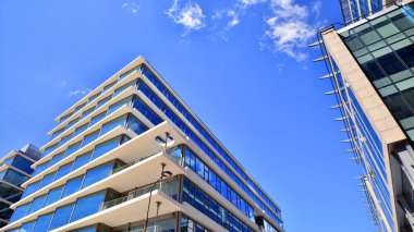 Şehir merkezindeki işletme bölgesi mimarisi. Mavi gökyüzüne ve güneş ışığına karşı cam yansıtıcı ofis binaları. Ekonomi, finans, iş faaliyeti konsepti. Soyut modern mimari parçası