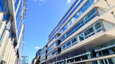 Şehir merkezindeki işletme bölgesi mimarisi. Mavi gökyüzüne ve güneş ışığına karşı cam yansıtıcı ofis binaları. Ekonomi, finans, iş faaliyeti konsepti. Soyut modern mimari parçası