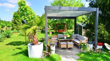 Güzel bahçesinde şık bahçe mobilyaları olan modern alüminyum pergola..