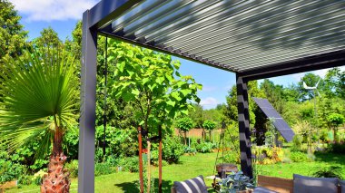 Güzel bahçesinde şık bahçe mobilyaları olan modern alüminyum pergola..