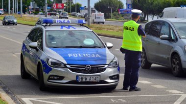 Szczecin, Polonya. 16 Temmuz 2025. Trafik polisi sokakta radar hızında silah tutuyor. Arka plan. 