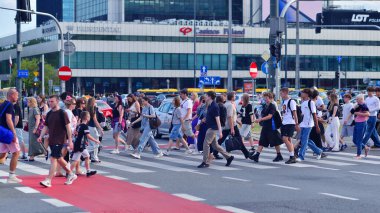 Varşova, Polonya. 5 Ağustos 2025. Farklı yaşlarda insanlar karşıdan karşıya geçiyor. Büyük bir şehrin Sommer caddesi. Şehir caddesi manzarası sakinleri, turistler ve modern binalar.