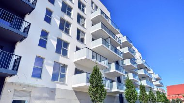 Yeşil yerleşim bölgesinde yeni daireleri olan modern bir yerleşim yeri. Çevre mimarisi. Yeşil ağaç ve yeni apartman. Doğanın ve modernliğin ahengi.