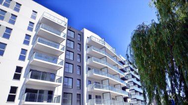Yeşil yerleşim bölgesinde yeni daireleri olan modern bir yerleşim yeri. Çevre mimarisi. Yeşil ağaç ve yeni apartman. Doğanın ve modernliğin ahengi.