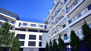 Yeşil yerleşim bölgesinde yeni daireleri olan modern bir yerleşim yeri. Çevre mimarisi. Yeşil ağaç ve yeni apartman. Doğanın ve modernliğin ahengi.