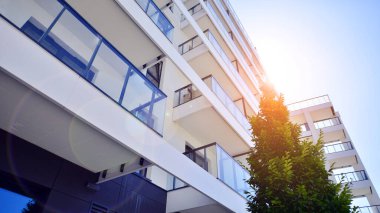 Yeşil yerleşim bölgesinde yeni daireleri olan modern bir yerleşim yeri. Çevre mimarisi. Yeşil ağaç ve yeni apartman. Doğanın ve modernliğin ahengi.