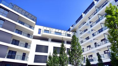 Yeşil yerleşim bölgesinde yeni daireleri olan modern bir yerleşim yeri. Çevre mimarisi. Yeşil ağaç ve yeni apartman. Doğanın ve modernliğin ahengi.