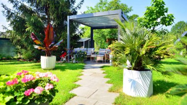 Güzel bahçesinde şık bahçe mobilyaları olan modern alüminyum pergola..