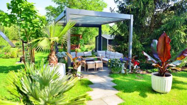 Güzel bahçesinde şık bahçe mobilyaları olan modern alüminyum pergola..