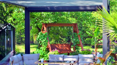 Güzel bahçesinde şık bahçe mobilyaları olan modern alüminyum pergola..