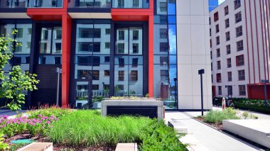 Yeşil yerleşim bölgesinde yeni daireleri olan modern bir yerleşim yeri. Çevre mimarisi. Yeşil ağaç ve yeni apartman. Doğanın ve modernliğin ahengi.