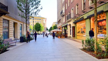 Warsaw, Poland. 21 September 2025. Chmielna in downton lined with granite slabs and planted with plants and shrubs street. City promenade during summer day. City architecture with shops and greenery.